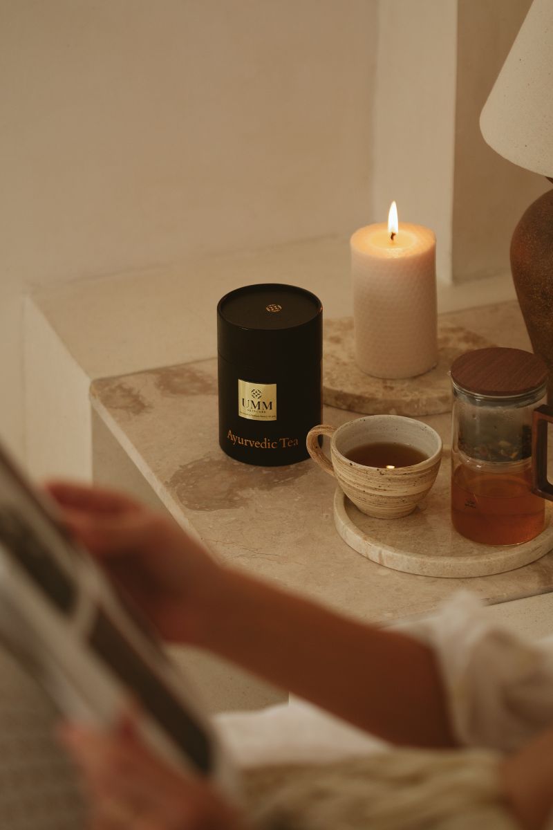 Woman reading in bed while she waits for her loose leaf Ayurvedic tea to brew.