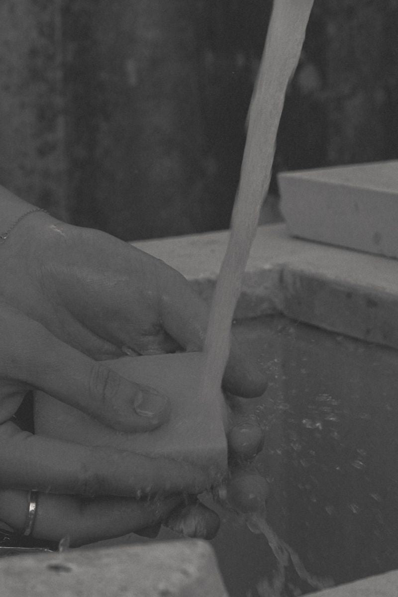 Bands holding UMM Skincare soap bar under the water, while indulging in a bathing treatment. 