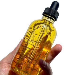 Hand holding bottle of UMM Skincare pre shower body oil.